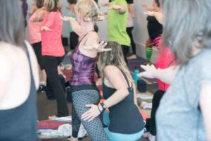 assisting a student in a yoga class